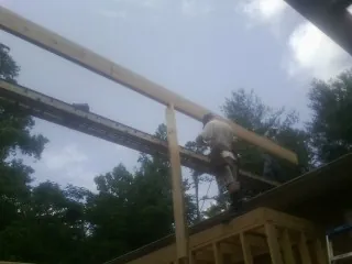 Carpenter setting a ridge beam over a new addition frame — Ice Dam Removal by Roofing Brothers in Merchantville