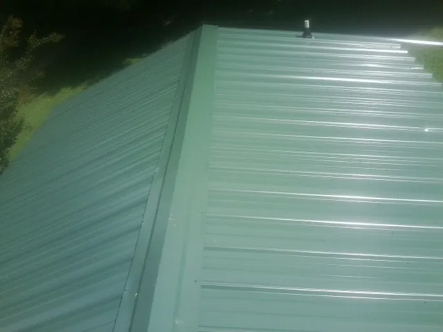 New green metal panels meeting at the ridge of a roof — Flat Roof Repair work by our crew in Merchantville