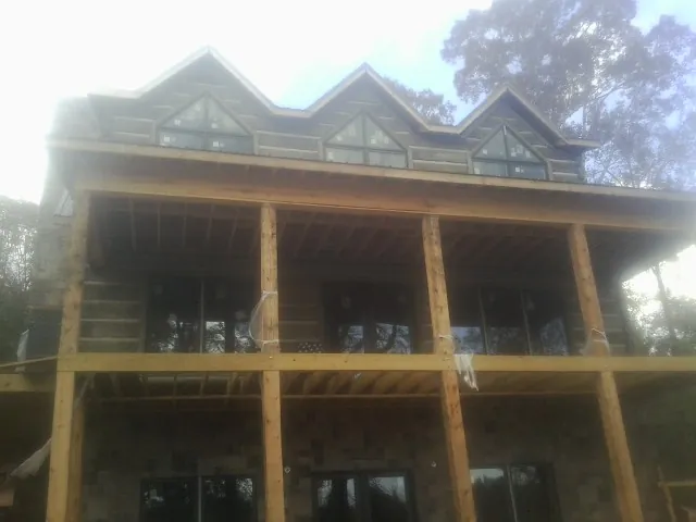 Dormers and porch framing on a large log home under construction — Roof Coating work by our crew in Merchantville