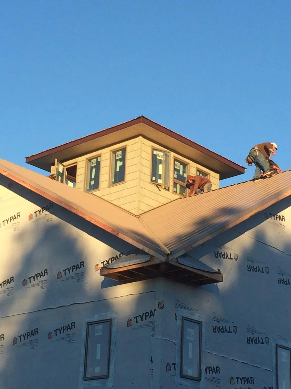 Roofers working around a rooftop cupola on a new metal roof at sunset — Roof Waterproofing in Merchantville by Roofing Brothers